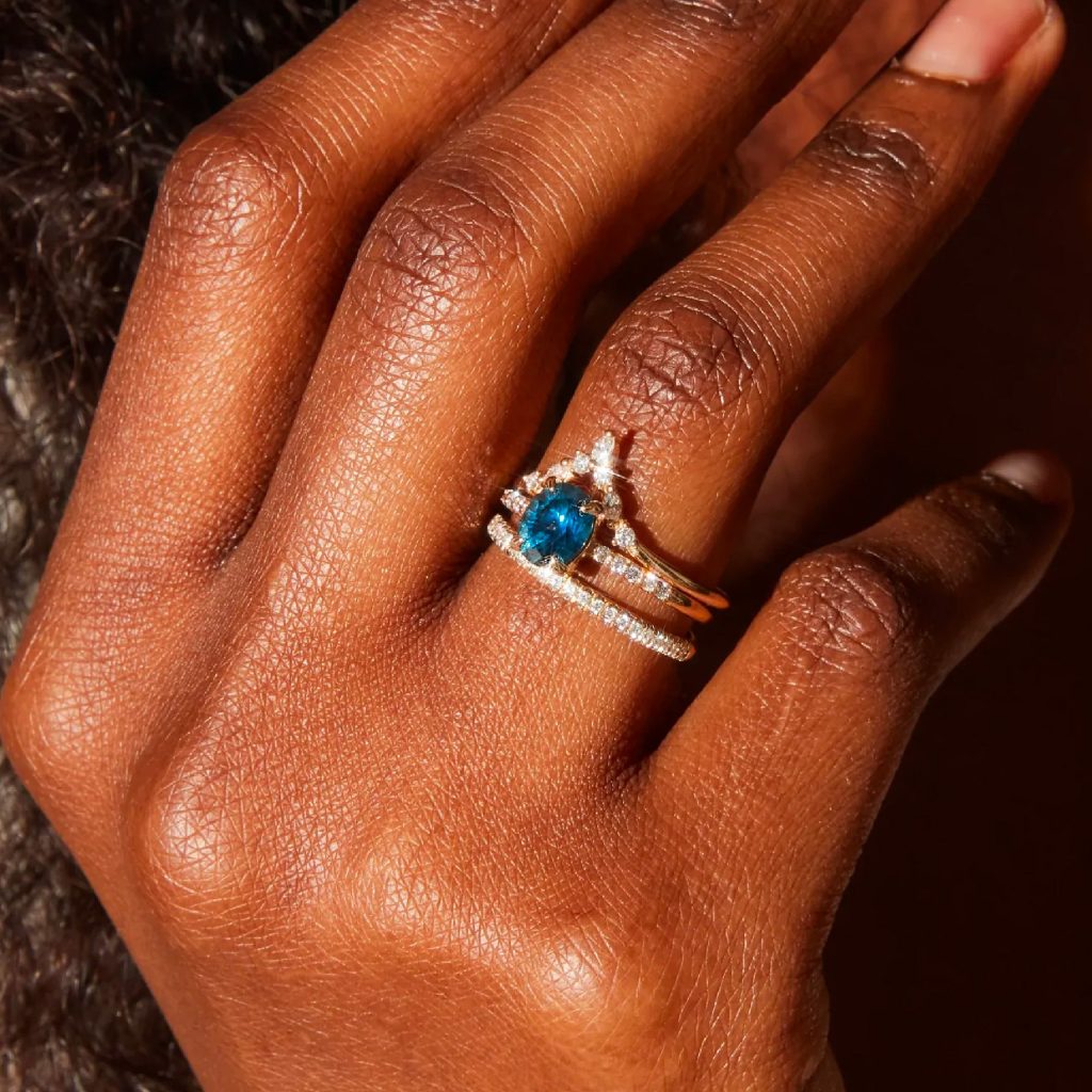 A womans left hand with three rings stacked on her ring finger